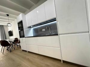 eine Küche mit weißen Schränken, einer Spüle und einem Tisch in der Unterkunft A H Rentals Picasso apartamento in Vinarós