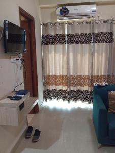 un soggiorno con TV e divano blu di Home Stay 1 a Noida