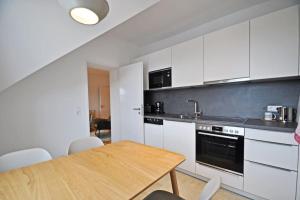 eine Küche mit weißen Schränken und einem Holztisch in der Unterkunft Design-Highlight: Stilvolles Altstadt-Apartment! in Wittlich