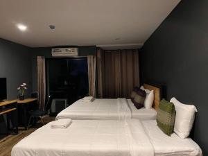 a hotel room with two beds and a desk at Dm Inn in Khon Kaen