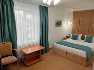 Habitación de hotel con cama y silla en Kurmet Hotel, en Uralsk