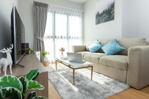 un salon avec un canapé et un ordinateur portable sur une table basse dans l'établissement Sky River, Luxury Infinity, Center Chiang Mai, à Chiang Mai