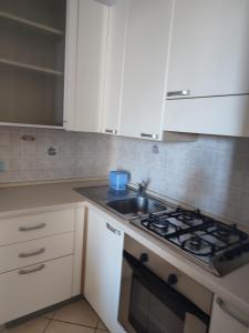 a kitchen with a sink and a stove and white cabinets at Appartamenti Piccola Stella Maris in Senigallia