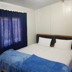 1 dormitorio con 2 camas y cortina azul en GÜN IŞIĞI KONAKLAMA, en Hatay