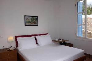 Schlafzimmer mit einem Bett mit weißer Bettwäsche und einem Fenster in der Unterkunft Panoramic View apartment in Poros