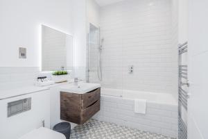 a white bathroom with a sink and a bath tub at Roomspace Serviced Apartments Newlands House in Surbiton