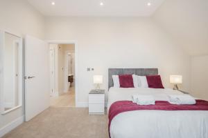 a white bedroom with a large bed with red pillows at Roomspace Serviced Apartments Newlands House in Surbiton