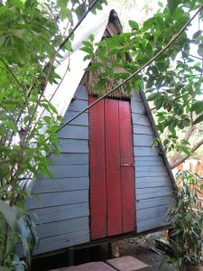 a red door on a blue house with trees at Ratanakiri Homestay & Jungle Trek in Banlung