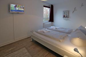 1 dormitorio con 1 cama y TV en la pared en Am Flugplatz 7_ Haus Habel Whg_ 12, en Wyk auf Föhr