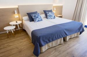a bedroom with a large bed with blue pillows at Parque Nereida Suites Hotel in Cala Ratjada