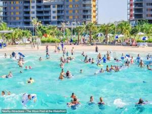 un grupo de personas en el agua en una playa en Beautiful spacious city apartment with views out to the Arafura Sea en Darwin