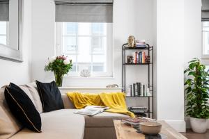 uma sala de estar com um sofá com almofadas amarelas em Elegant central London flat - ideal for weekend city break em Londres