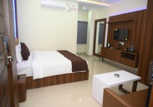 um quarto de hotel com uma cama e uma televisão em Atithi Regency em Dhuburi