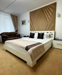 um quarto com uma cama grande e uma grande cabeceira. em Kurmet Hotel em Uralsk