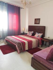 1 Schlafzimmer mit 2 Betten und roten Vorhängen in der Unterkunft Appartement IRIS, S+1 cité wahat in Tunis