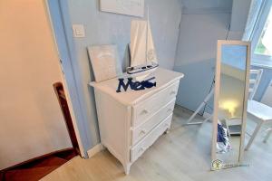 een witte dressoir en een spiegel in een kamer bij Le ploubaz in Ploubazlanec