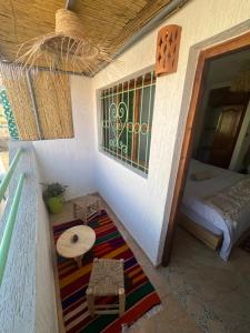 Tamraght OuzdarにあるNatural Surf Houseのベッド、テーブル、窓が備わる客室です。