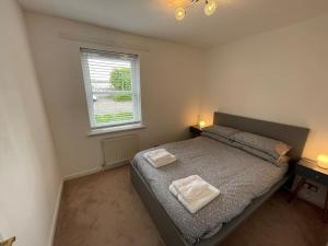 a bedroom with a bed with two towels on it at 2 Bedroom Apartment near Glasgow Airport in Renfrew