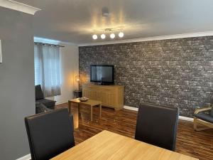 a living room with a tv and a brick wall at 2 Bedroom Apartment near Glasgow Airport in Renfrew