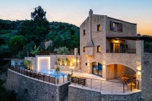 卡尼亞鎮的住宿－Kotinos Luxury Villa，一座石头房子,前面设有一个游泳池