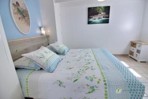 a bedroom with a bed with blue and white sheets and pillows at Les arums in Lantic
