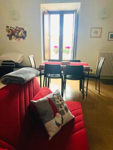 sala de estar con sofá rojo, mesa y sillas en Regina d’Aragona casa vacanze en Sulmona
