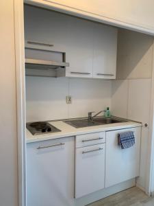 a white kitchen with a sink and a stove at French Riviera apartment with swimming pool and free parking near Monaco in Roquebrune-Cap-Martin