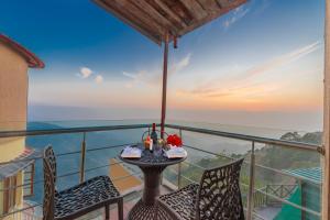 una mesa y sillas en un balcón con vistas al océano en 3BDR Cottage Kasauli by Humble stay, en Kasauli