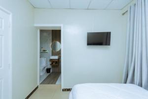 1 Schlafzimmer mit einem weißen Bett und einem Badezimmer in der Unterkunft Ibi Villa Retreat in Kigali