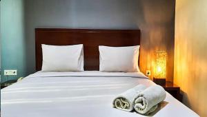 uma cama com lençóis brancos e toalhas em N hotel Tanah Abang em Jakarta