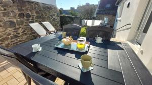 einen Holztisch mit einem Tablett mit Essen auf einer Terrasse in der Unterkunft La venelle in Saint-Quay-Portrieux