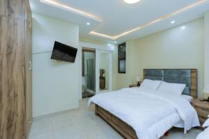 - une chambre avec un grand lit blanc et une télévision dans l'établissement Ibi Villa Retreat, à Kigali