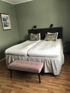 - une chambre avec un grand lit et un tabouret rose dans l'établissement Vandrarhemmet Östergatan, à Skövde