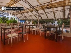 OYO Arpora Baga في باغا: مطعم بطاولات وكراسي تحت سقف
