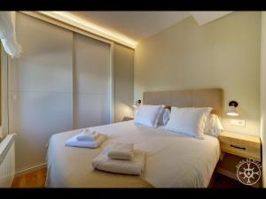 a bedroom with a white bed with towels on it at LIEBRE de Alma de Nieve in Naut Aran