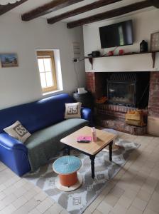 sala de estar con sofá azul y chimenea en La cour du manoir, en Heuland