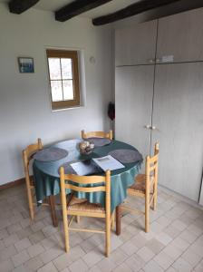 una mesa y sillas en una habitación con cocina en La cour du manoir, en Heuland