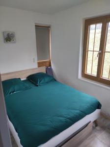 een bed met groene kussens in een kamer met een raam bij La cour du manoir in Heuland