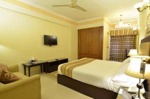 ein Hotelzimmer mit einem Bett und einem TV in der Unterkunft Pak Continental Hotel in Bahawalpur