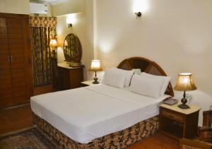 a bedroom with a large white bed and two lamps at Pak Continental Hotel in Bahawalpur