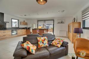uma sala de estar com um sofá de couro e uma cozinha em Villa armor azur em Erquy