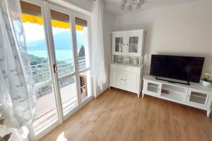 a living room with a television and a large window at Sunset House Perledo in Perledo