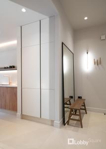 Habitación con un gran tabique blanco con un banco de madera. en Muse Apartment by LobbySquare, en Atenas