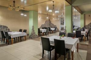 B&B Widok في بييلسكو بياوا: غرفة طعام مع طاولات بيضاء وكراسي سوداء