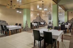 a dining room with white tables and black chairs at B&B Widok in Bielsko-Biała