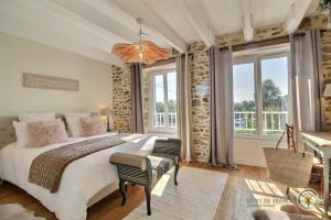 a bedroom with a large bed and windows at Les pommettes in Plouër-sur-Rance