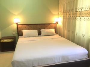 a bedroom with a large white bed with two pillows at Hotel City Inn in Chittagong