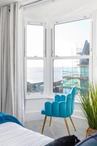 a bedroom with a blue chair in front of a window at Smugglers Snug by the sea in Rottingdean