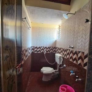 a bathroom with a toilet in a room at The Stone Cabin Cottage in Gokarna