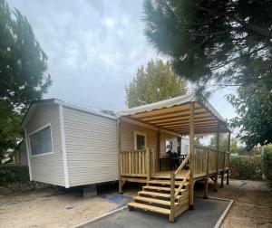 a tiny house with a porch and a deck at Mobil Home Palmiers 1 in Valras-Plage